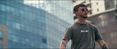 a man with a beard and sunglasses standing in front of a tall building