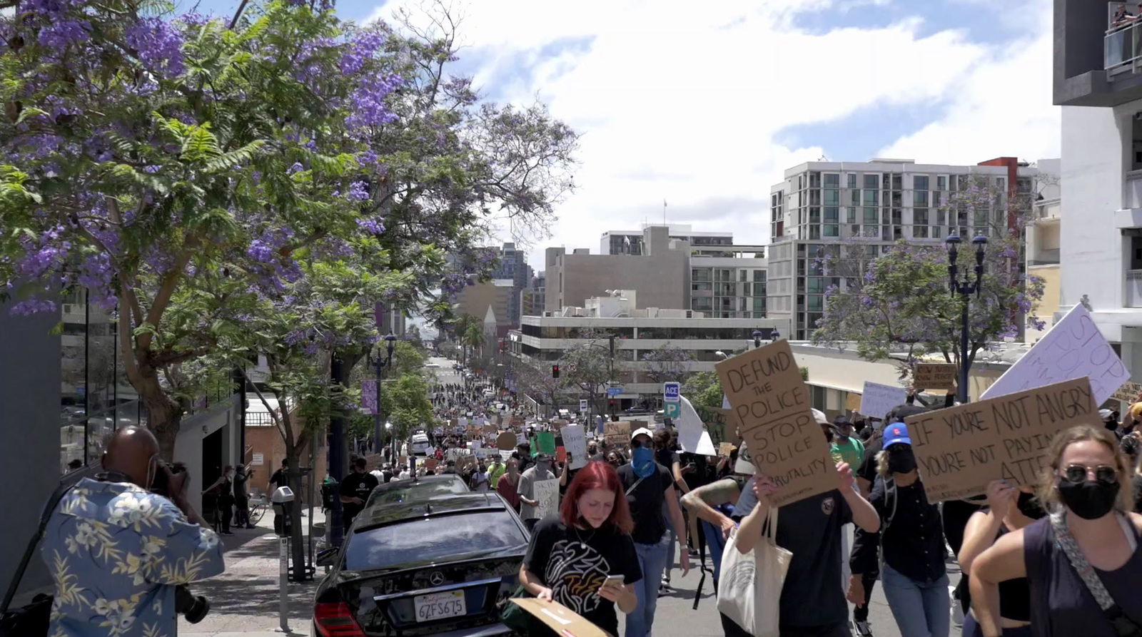 a group of people walking down a street holding signs