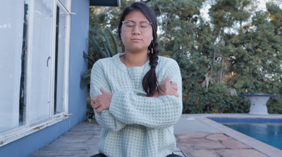 a woman with her arms crossed standing in front of a pool