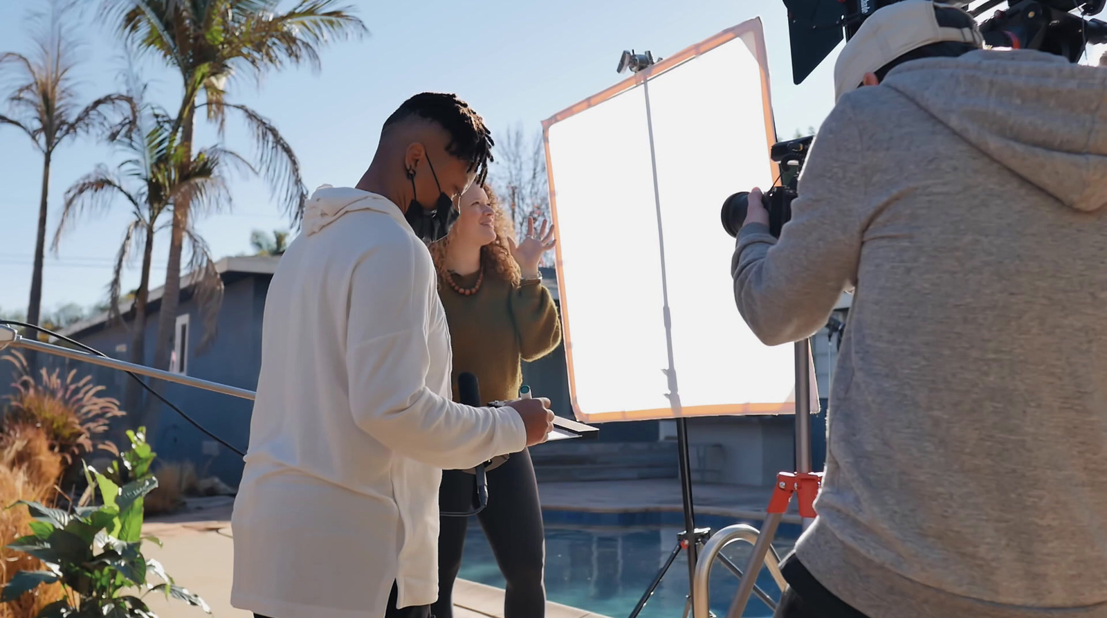 a man standing next to a woman in front of a camera