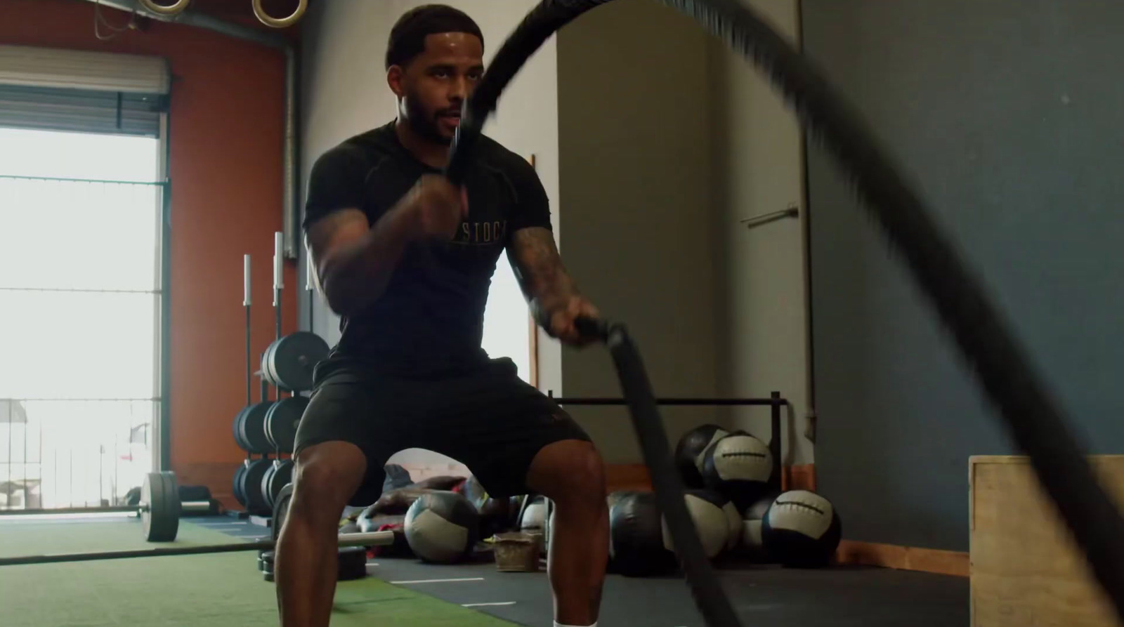 a man in a gym doing a pull up with a rope