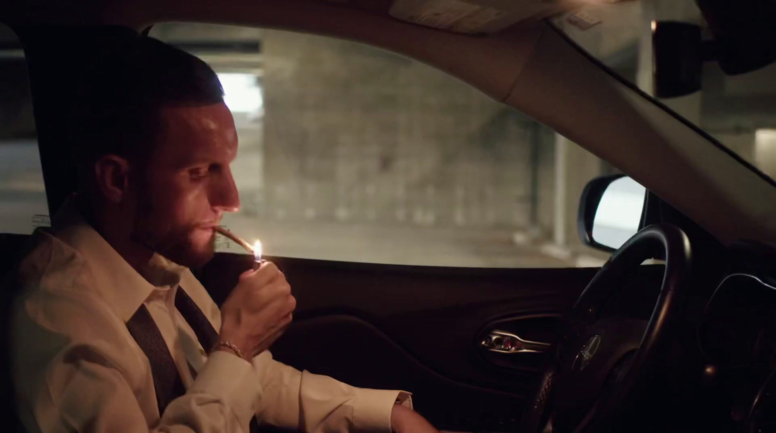 a man sitting in a car smoking a cigarette