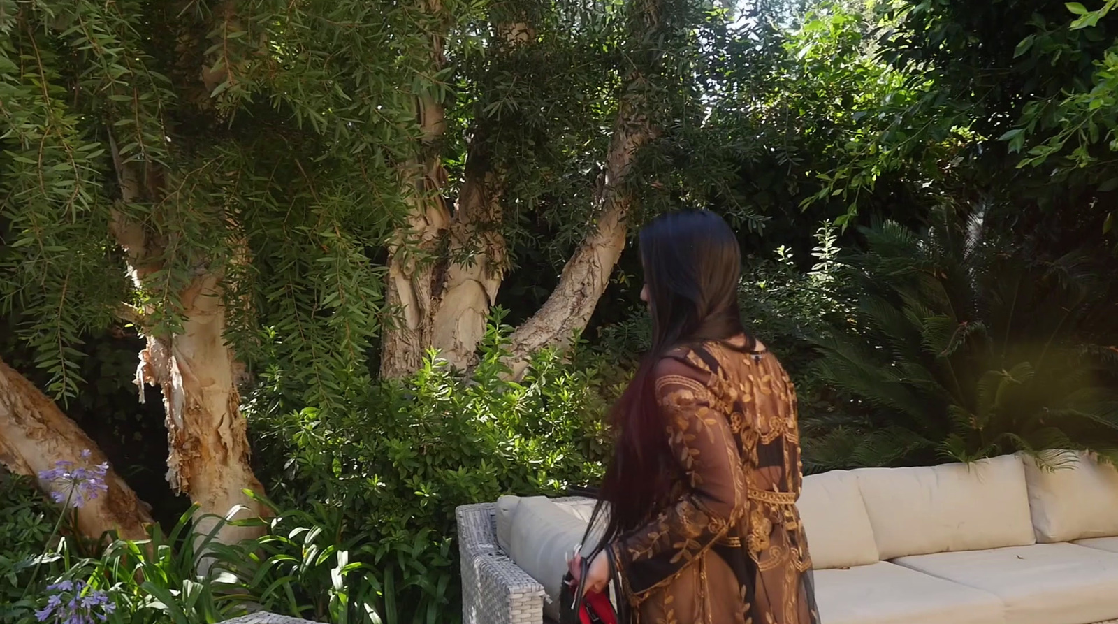 a woman standing in front of a couch in a garden