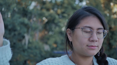 a woman wearing glasses looking down at her cell phone