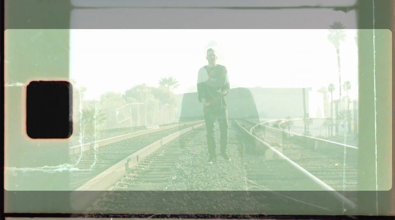 a man standing on a train track with a guitar