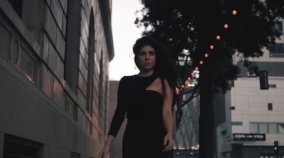 a woman in a black dress is walking down the street