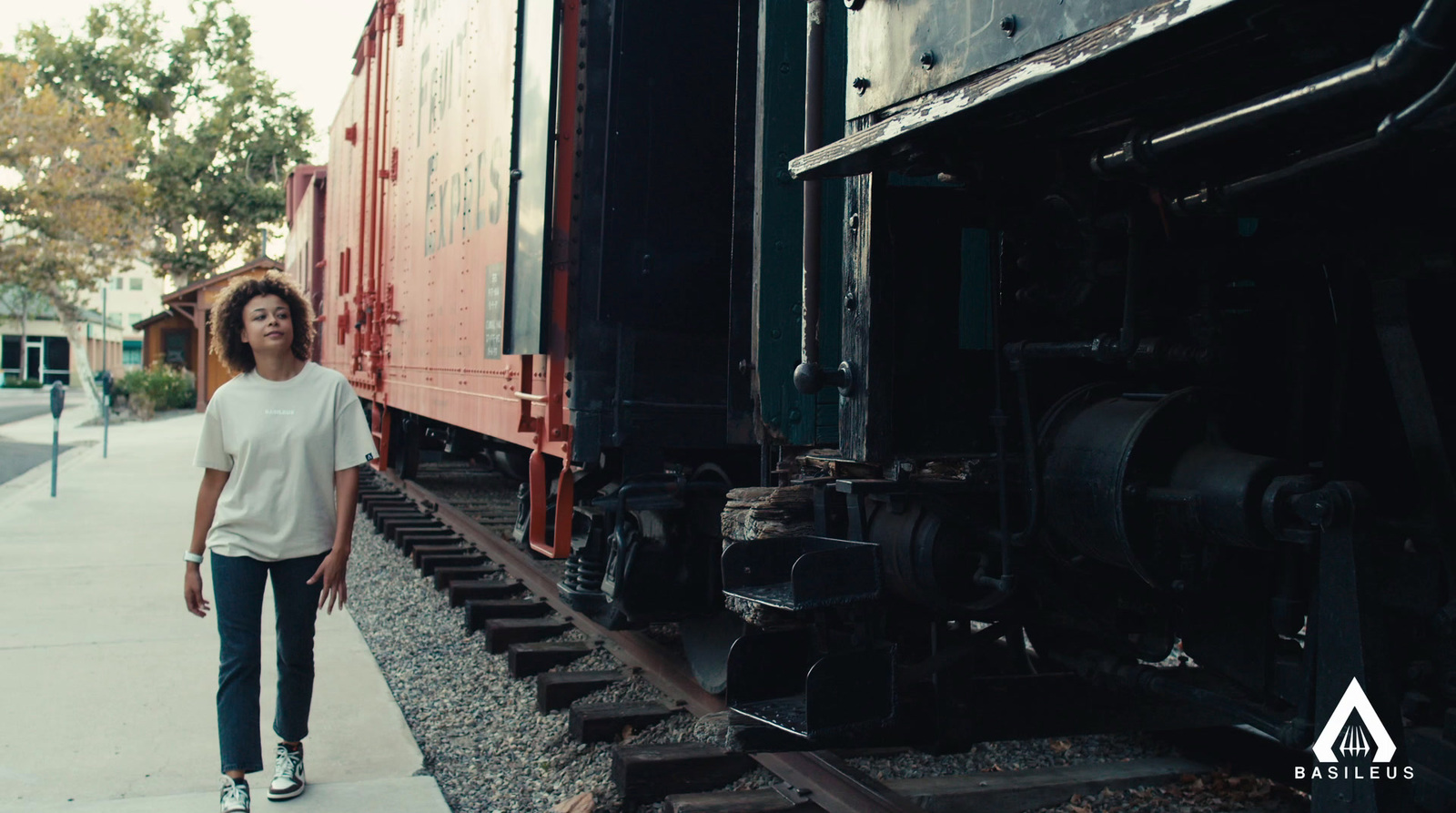 a woman standing next to a train on the tracks