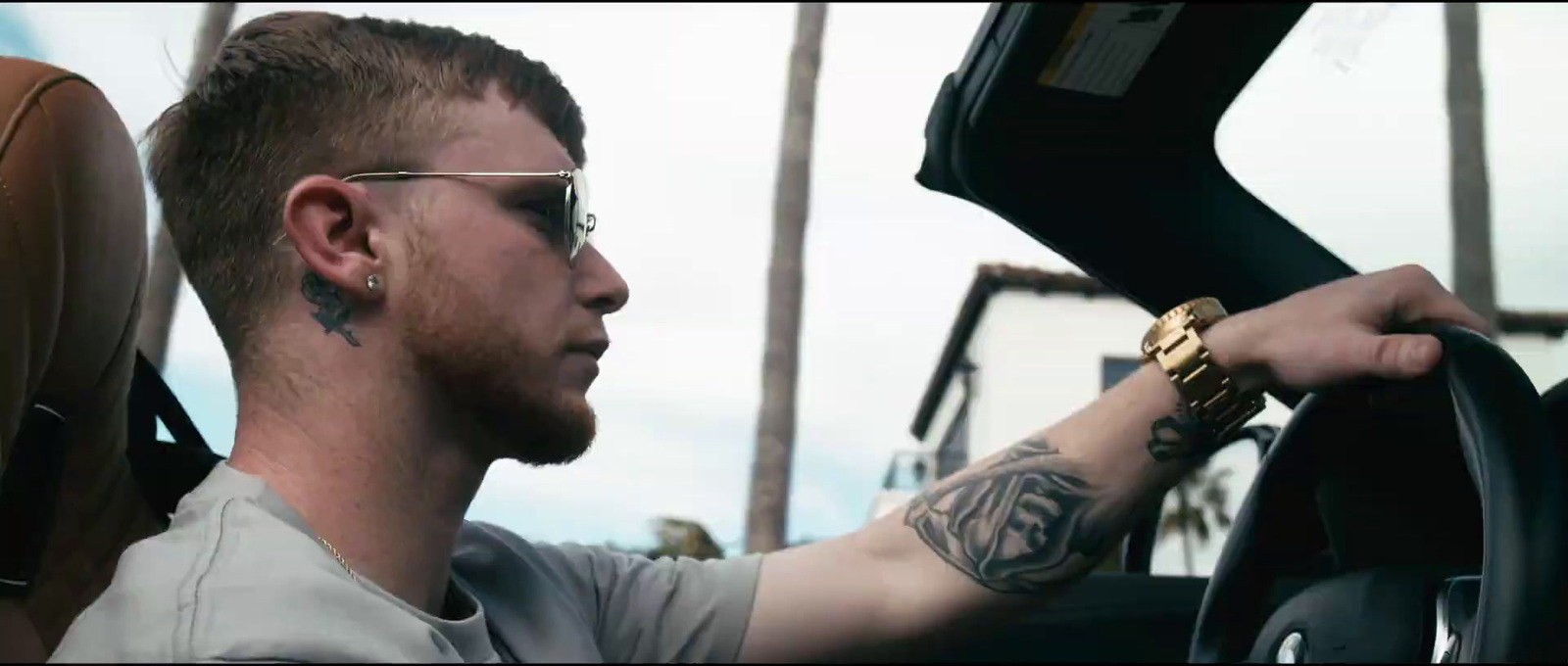 a man with tattoos on his arm driving a car