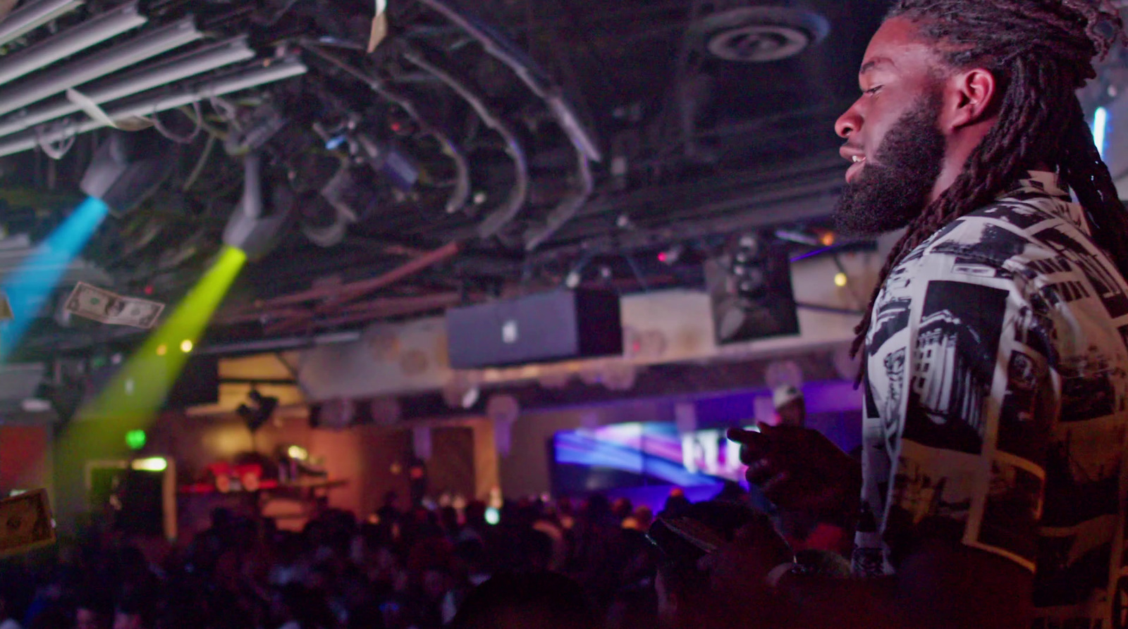 a man with dreadlocks standing in front of a crowd