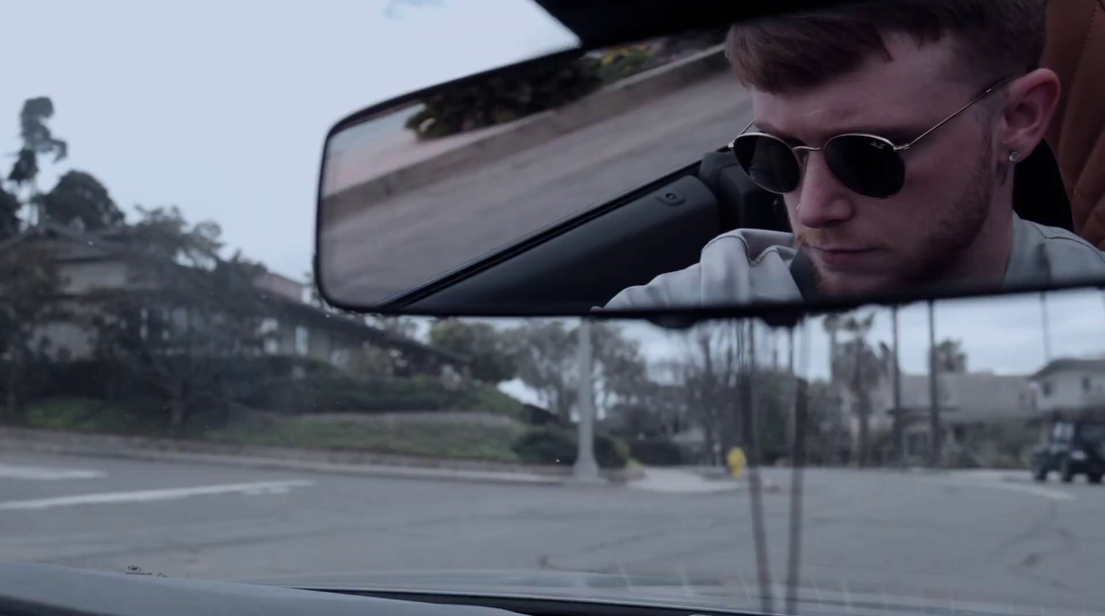 a man wearing sunglasses is seen in the rear view mirror of a car