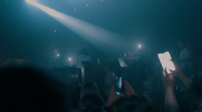 a crowd of people standing around a stage holding up cell phones