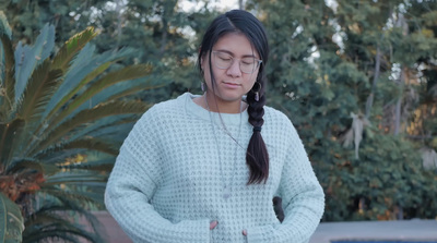 a woman wearing glasses and a sweater looking at her cell phone