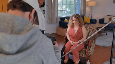 a woman sitting in a chair in front of a camera