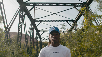 a man standing in front of a metal bridge