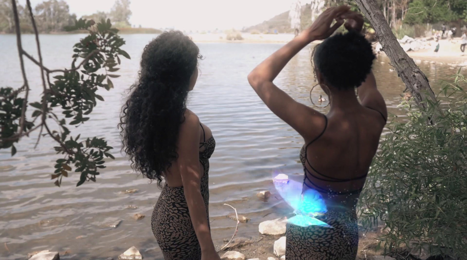 a couple of women standing next to a body of water