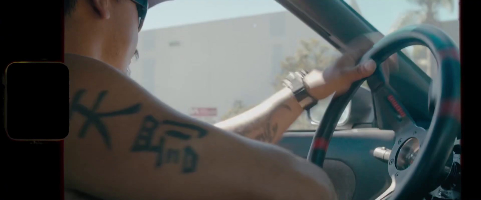 a man driving a car with a tattoo on his arm