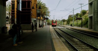 a red train traveling down train tracks next to a tall building