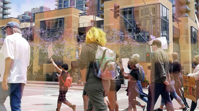 a group of people walking down a street next to tall buildings