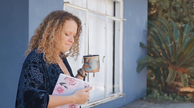 a woman holding a book and a lamp in front of a window