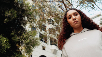 a woman with curly hair standing in front of a tree