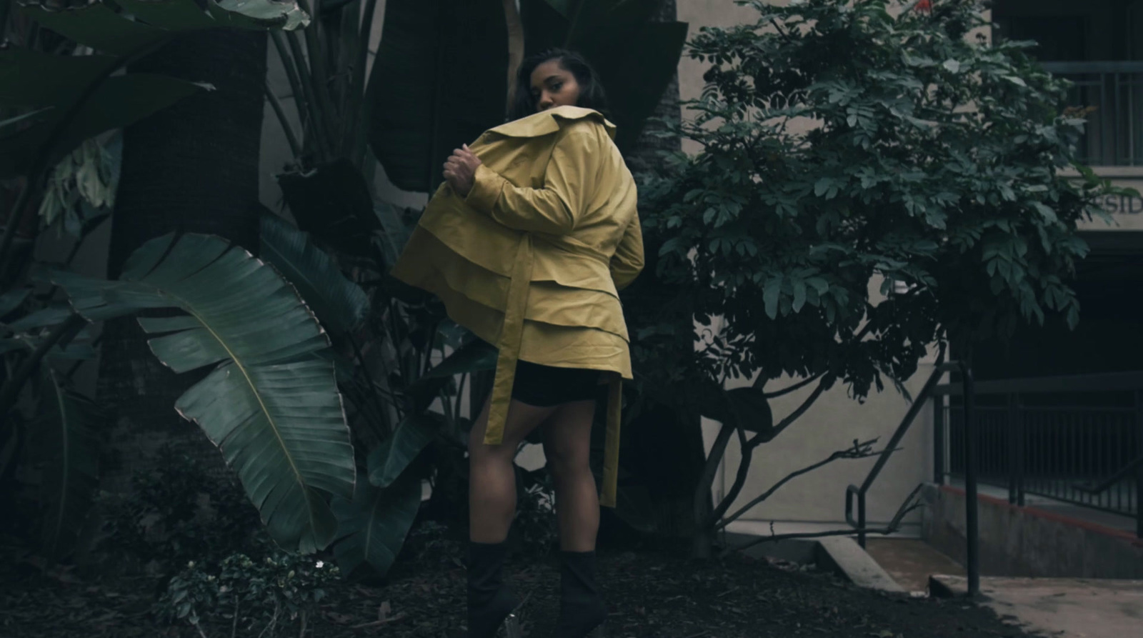 a woman in a yellow raincoat standing in front of a building