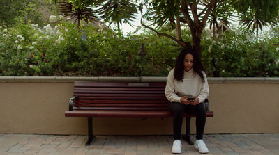 a woman sitting on a bench looking at her cell phone