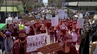 a group of people walking down a street holding signs