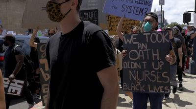 a group of people holding signs and wearing masks