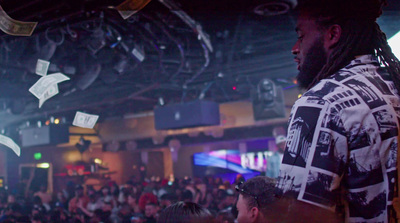 a man with dreadlocks standing in front of a crowd