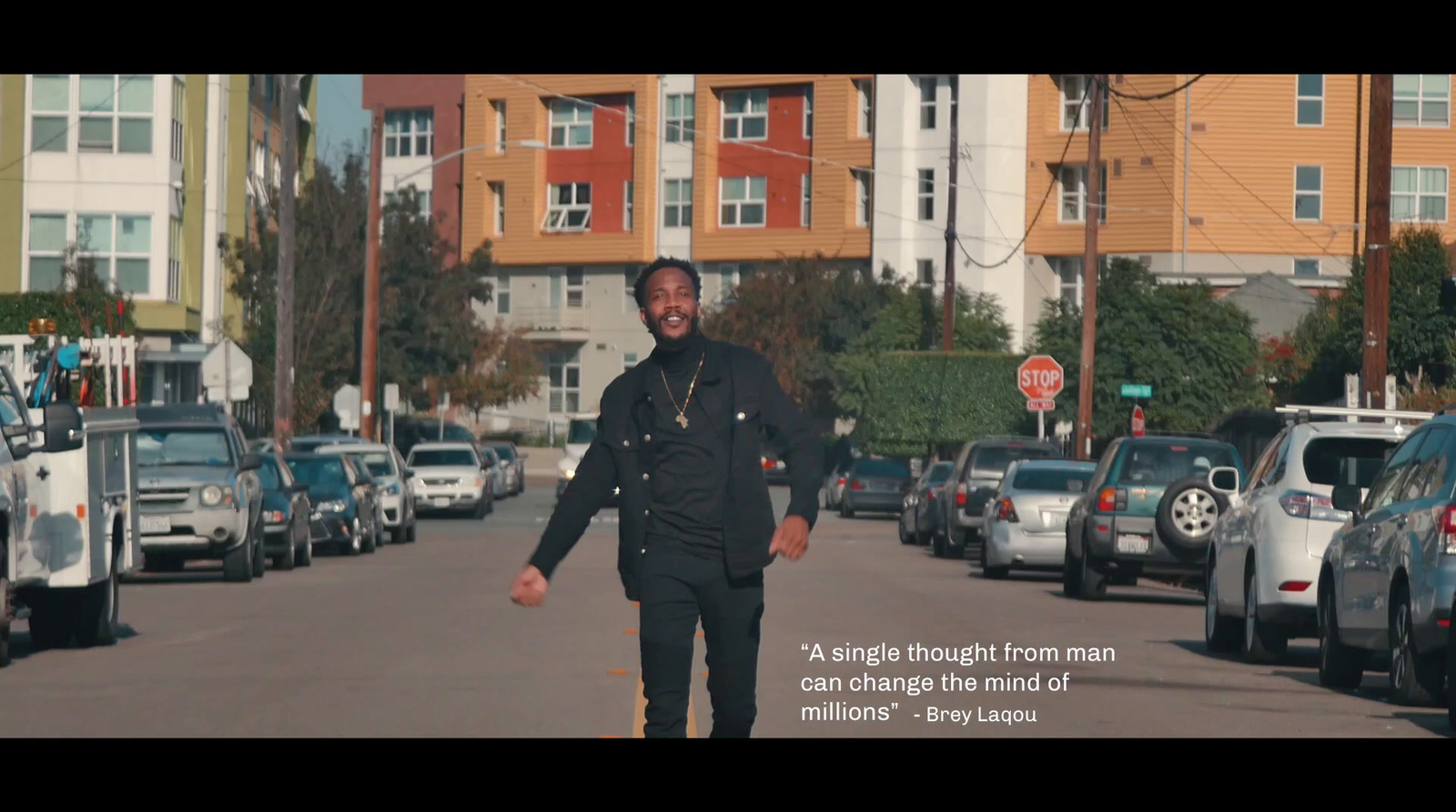 a man walking down a street next to parked cars