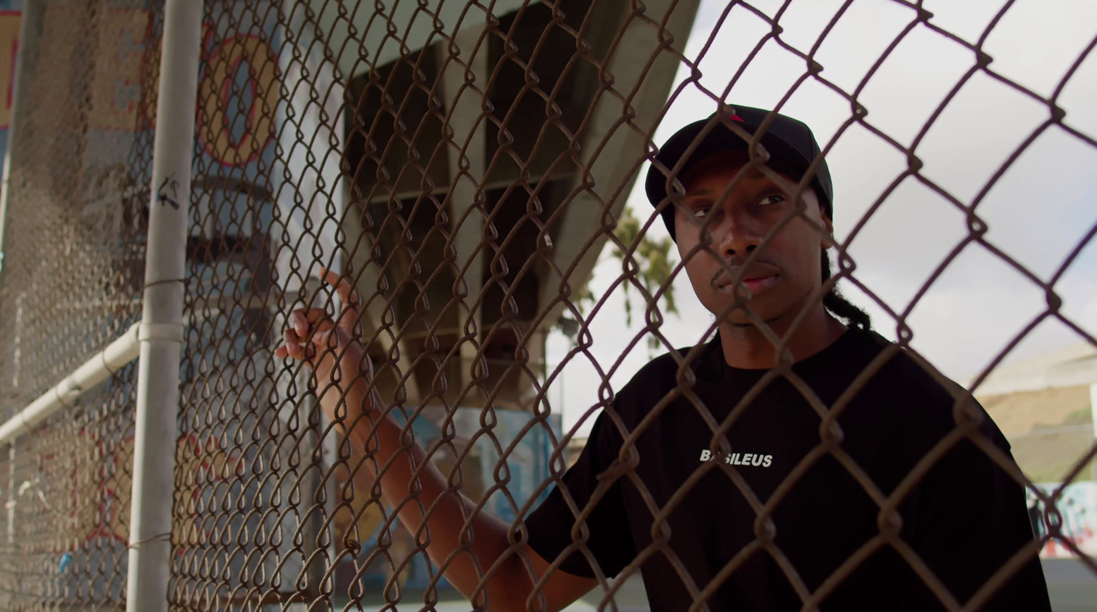 a man holding a baseball bat behind a fence