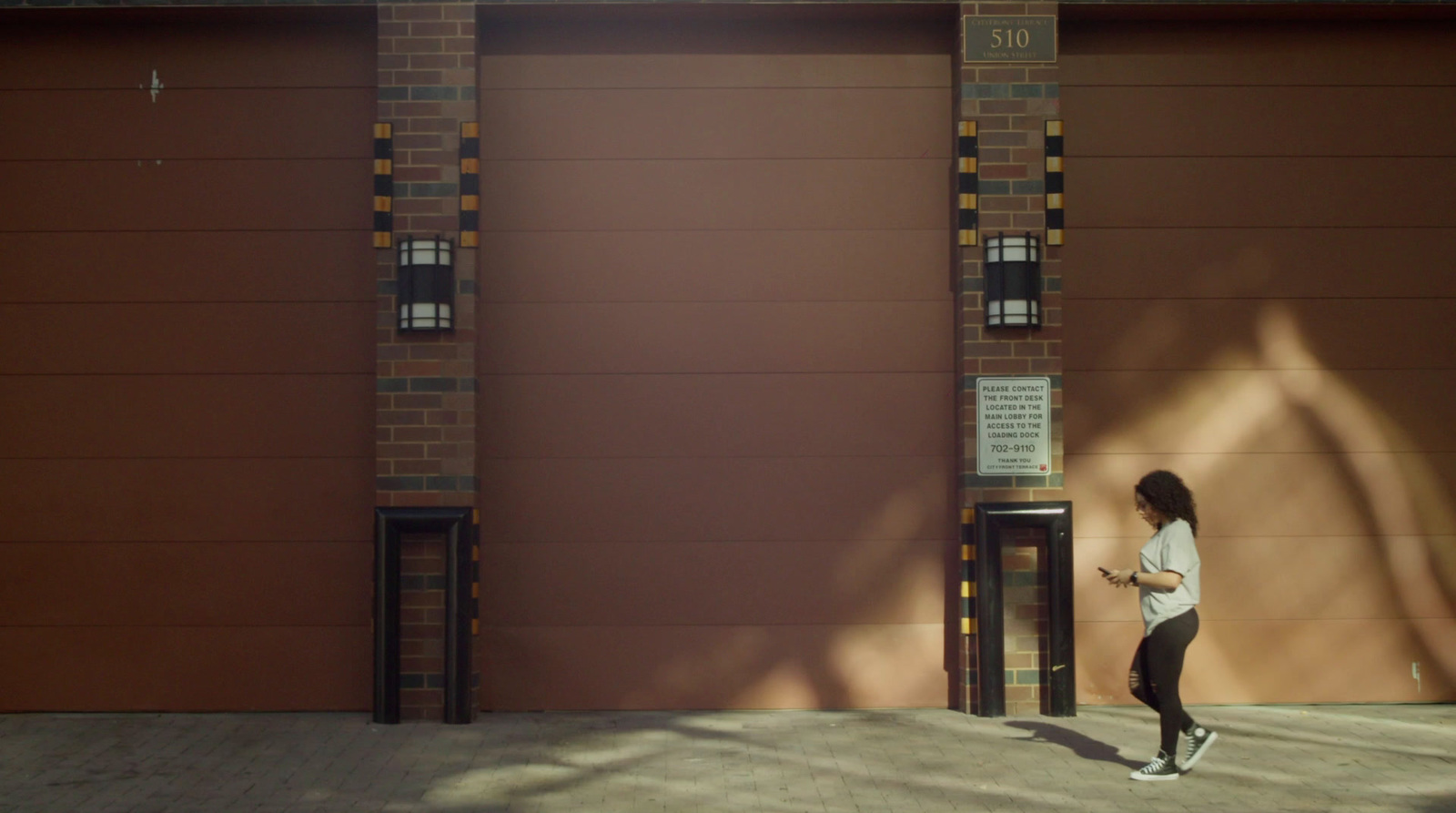 a woman walking past a tall brown garage door