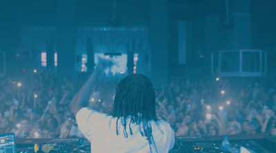 a dj in front of a large crowd at a concert