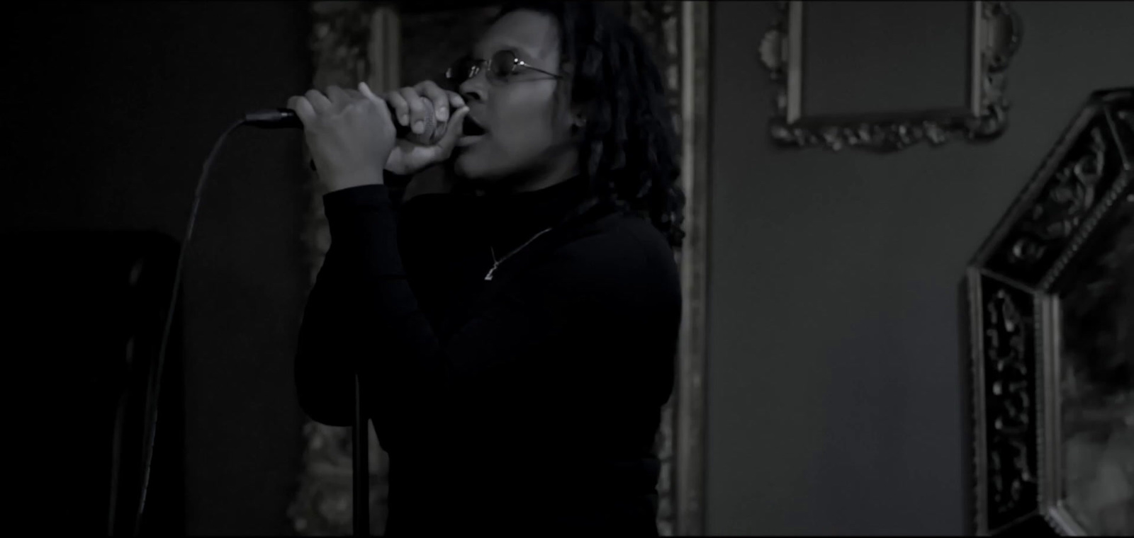 a woman singing into a microphone in a dark room