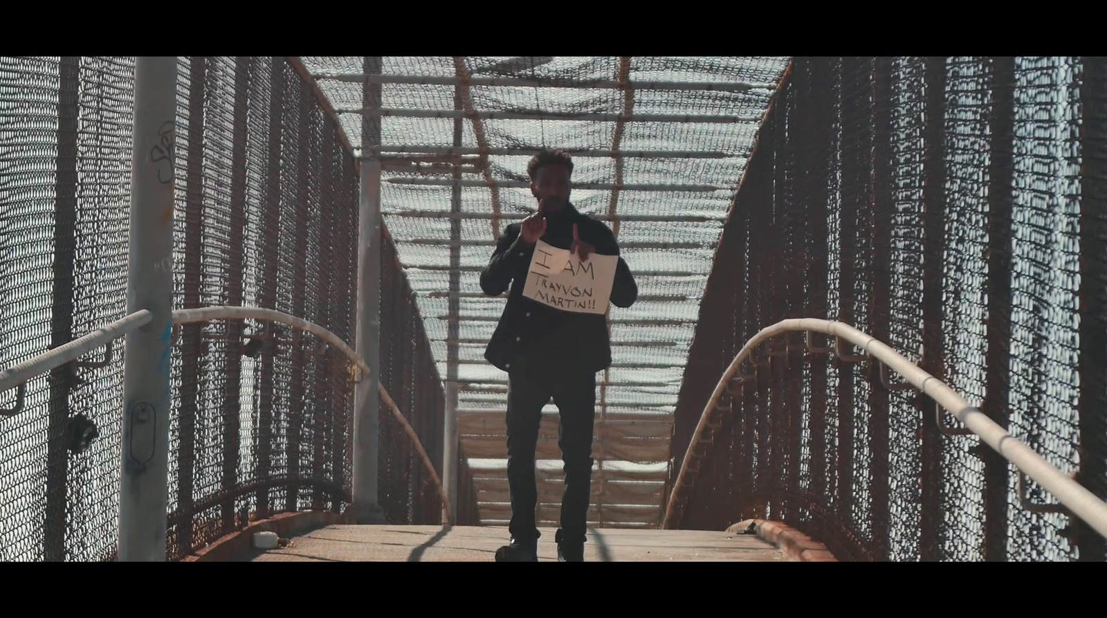 a man standing on a bridge holding a sign