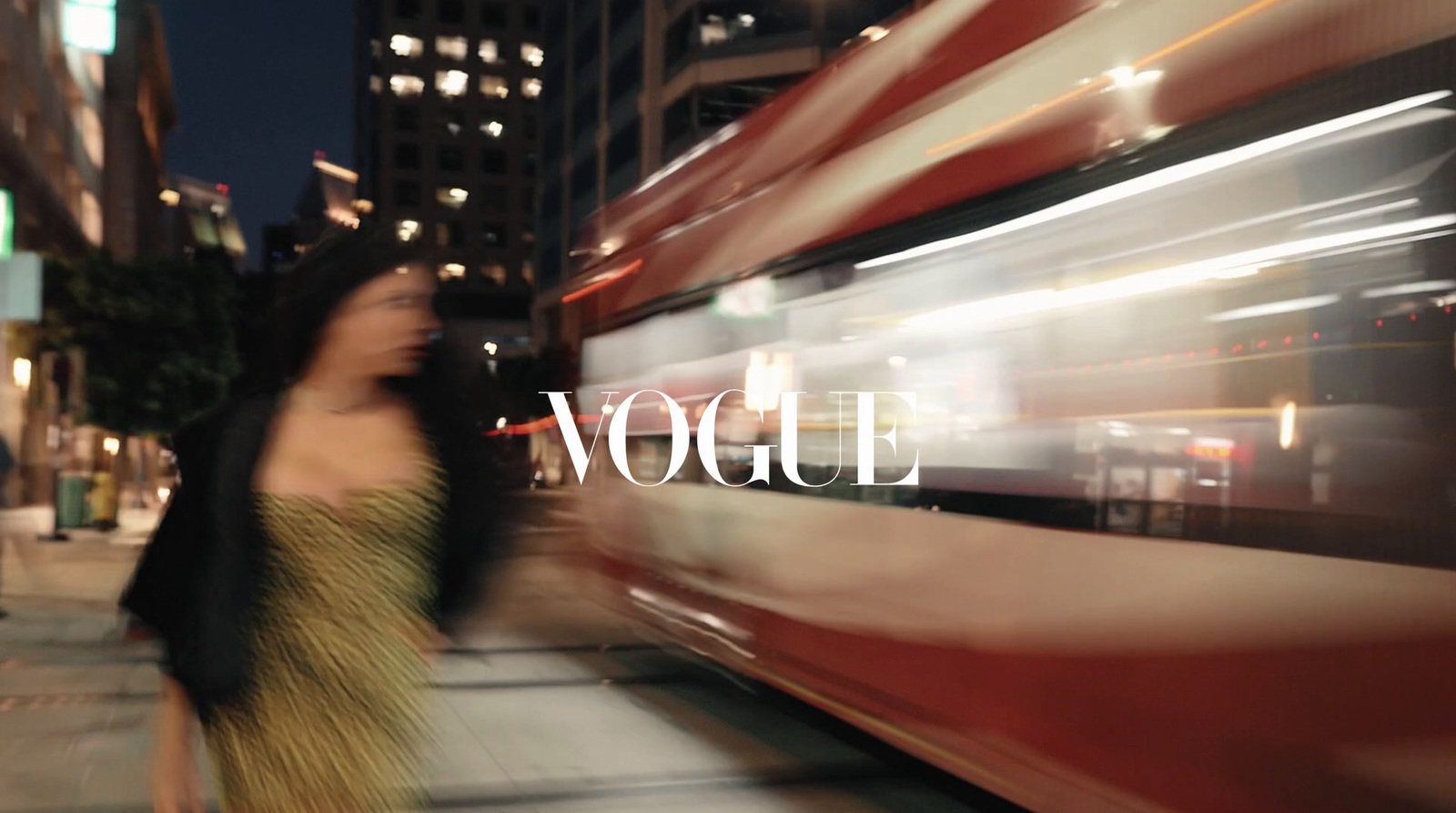 a woman walking down a sidewalk next to a bus