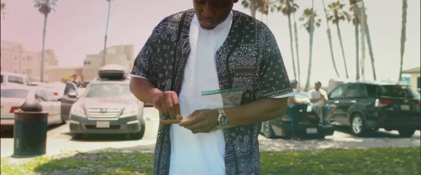 a man standing in a parking lot holding something in his hand