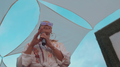 a woman singing into a microphone under an umbrella