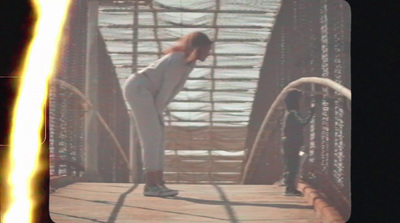 a woman standing on a bridge with her back to the camera