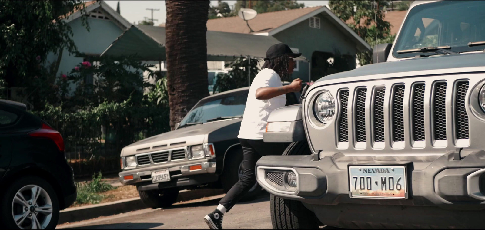 a man walking down a street next to parked cars