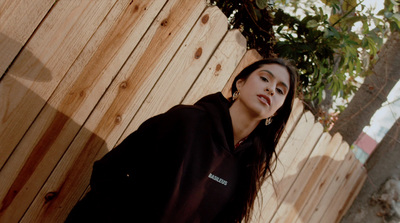 a woman standing in front of a wooden fence