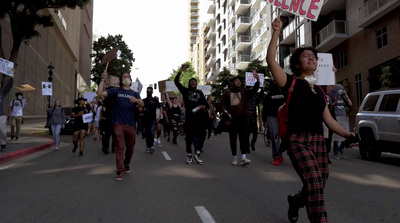 a group of people walking down a street holding signs