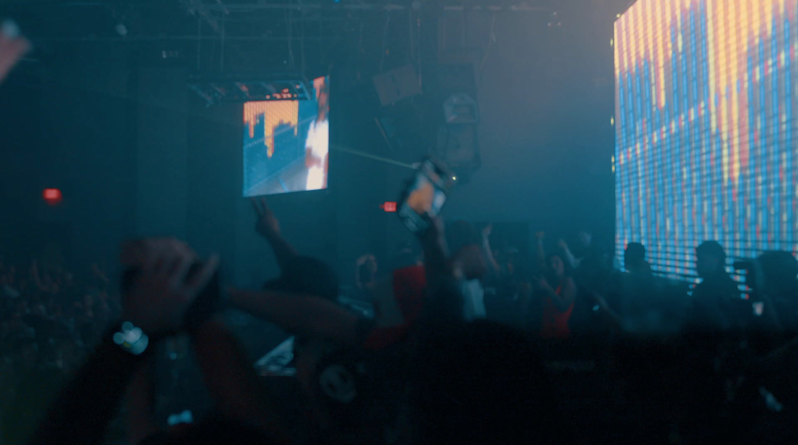 a crowd of people at a concert with their hands in the air