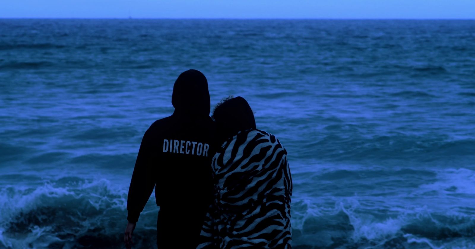 a couple of people standing on top of a beach next to the ocean