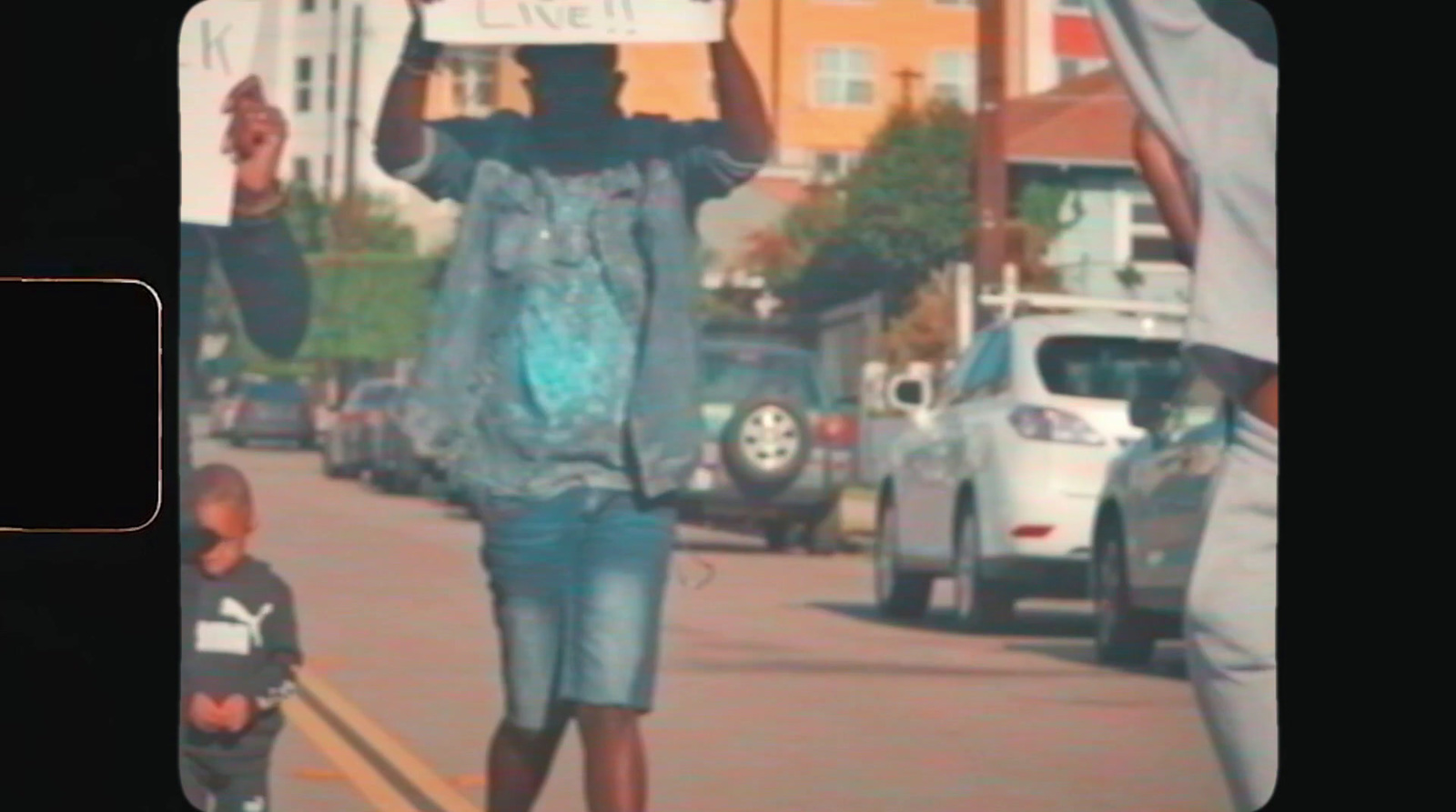 a man walking down a street holding a sign