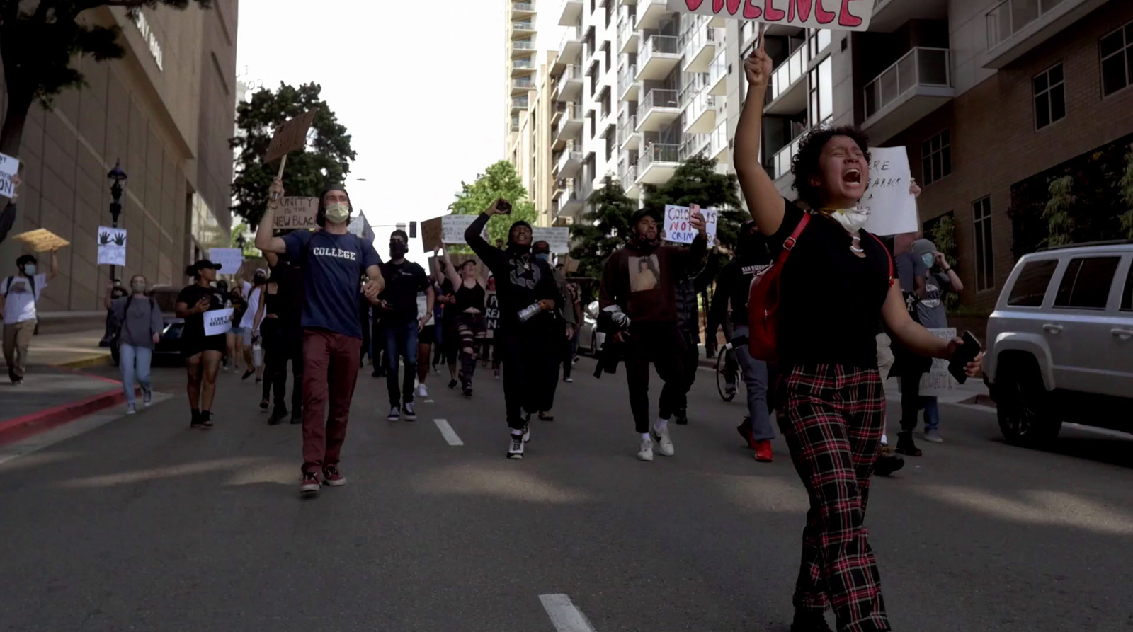 a group of people walking down a street holding signs