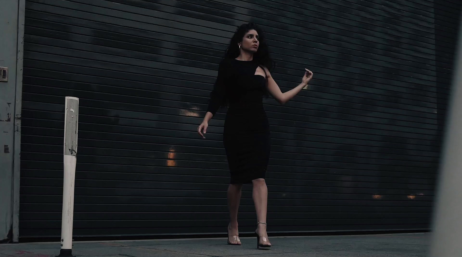 a woman in a black dress standing in front of a garage door