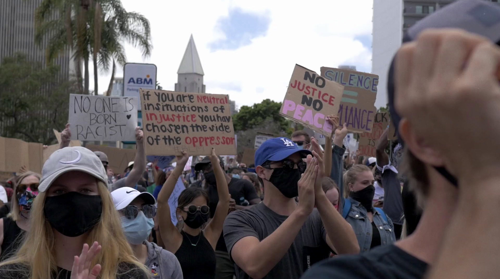 a group of people holding up signs and wearing masks