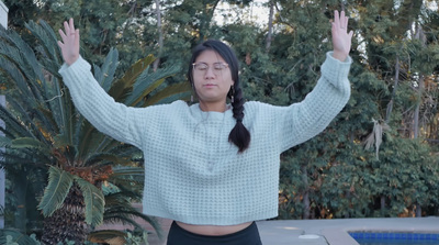 a woman standing in front of a pool with her hands in the air