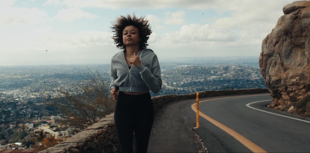 a woman standing on a road with her hair blowing in the wind